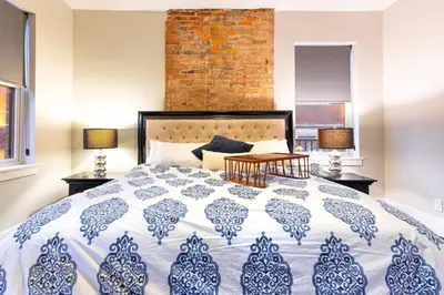a bedroom with a blue and white bed and a brick wall at Lux Townhome - Washington Park - Walk to ALL in Cincinnati