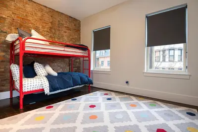 a bedroom with a red bunk bed and a brick wall at Lux Townhome - Washington Park - Walk to ALL in Cincinnati