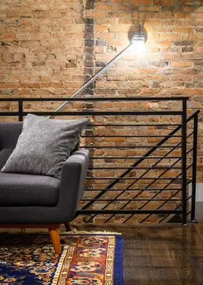 a lamp in a living room with a couch and a brick wall at Lux Townhome - Washington Park - Walk to ALL in Cincinnati