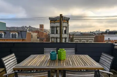 a wooden table with two cups on a balcony at Lux Townhome - Washington Park - Walk to ALL in Cincinnati