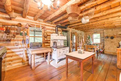 a kitchen in a log cabin with a stove at 1800s Romantic Cabin! Fireplace and 3 Jacuzzi Tubs in Paris