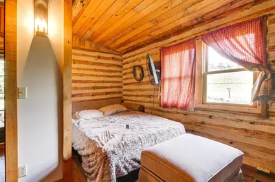 a bedroom with a bed in a log cabin at 1800s Romantic Cabin! Fireplace and 3 Jacuzzi Tubs in Paris