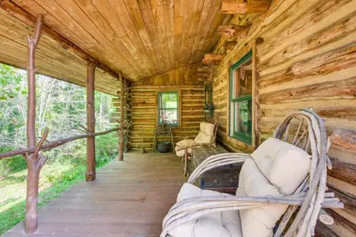 a log cabin with wicker chairs on a porch at 1800s Romantic Cabin! Fireplace and 3 Jacuzzi Tubs in Paris