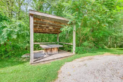a wooden pavilion with a picnic table in the grass at 1800s Romantic Cabin! Fireplace and 3 Jacuzzi Tubs in Paris
