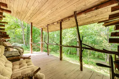 a living room with a couch on a wooden porch at 1800s Romantic Cabin! Fireplace and 3 Jacuzzi Tubs in Paris