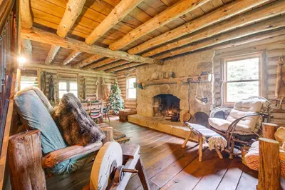 a living room with a fireplace in a log cabin at 1800s Romantic Cabin! Fireplace and 3 Jacuzzi Tubs in Paris