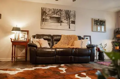 a brown leather couch in a living room with a table at The General's Quarters in Defiance