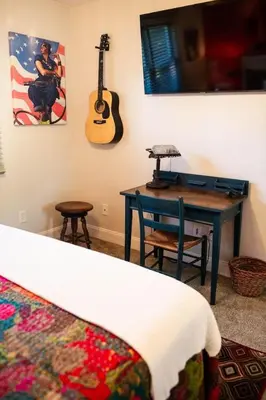 a bedroom with a desk and a guitar on the wall at The Aviators Lounge in Defiance