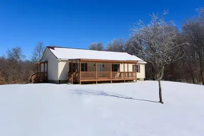 a house in a snow covered field with a tree at The Den at Buckskin- Entire House in Frankfort, OH in Greenfield