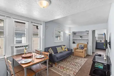 a living room with a blue couch and a table at Cozy Bungalow 10 Min to DTWN CLE in Euclid