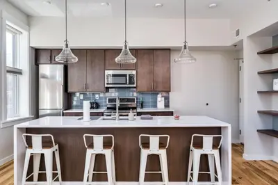 a kitchen with a large island with three bar stools at Top Rated - Free Parking - 1-br Condo OTR in Cincinnati