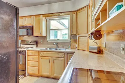 a kitchen with wooden cabinets and a sink and a window at Peaceful Home Near Youngstown Fenced Backyard! in Niles