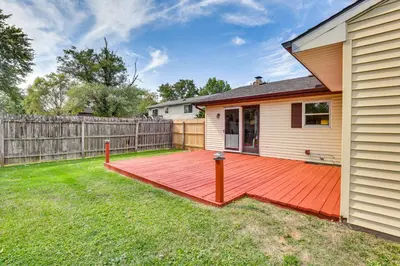 a backyard with a wooden deck next to a house at Peaceful Home Near Youngstown Fenced Backyard! in Niles