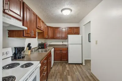 a kitchen with wooden cabinets and a white refrigerator at Scenic towers 3102 I Cozy & Comfy I Free Parking in Parma