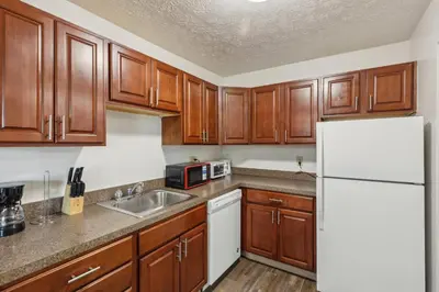 a kitchen with wooden cabinets and a white refrigerator at Scenic towers 3102 I Cozy & Comfy I Free Parking in Parma