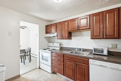 a kitchen with wooden cabinets and a white stove top oven at Midtown 3602I Cozy & Comfy I Free Parking in Parma