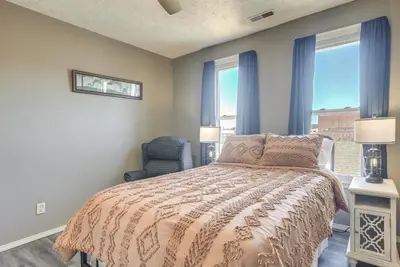 a bedroom with a bed and a chair and windows at Downtown Condo about 23 Mi to Hocking Hills State Park in Lancaster