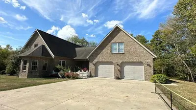 a brick house with two garage doors on a driveway at Owl's Nest Retreat in Russellville