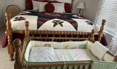 a bed with a crib with a quilt on it at Owl's Nest Retreat in Russellville