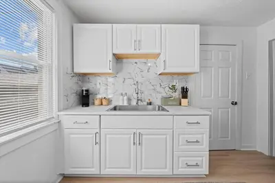 a white kitchen with a sink and white cabinets at Comfortable 2-Bedroom House In Cleveland 1330 in Cleveland