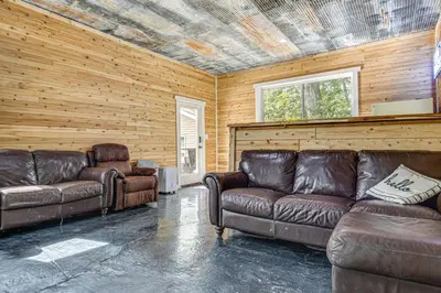 a living room with two leather couches and two windows at Lake Escape with Hot Tub and Docks in Hope! in Hope