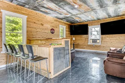 a room with a bar with chairs and a couch at Lake Escape with Hot Tub and Docks in Hope! in Hope