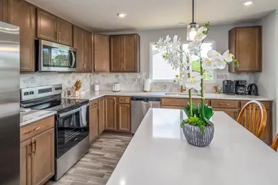 a kitchen with wooden cabinets and a vase with white flowers at Full Home by Ark and Creation Museum in Walton