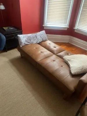 a brown leather couch in a room with red walls at Victorian Getaway in Cincinnati