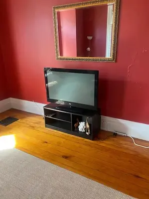 a flat screen tv in a living room with a mirror at Victorian Getaway in Cincinnati