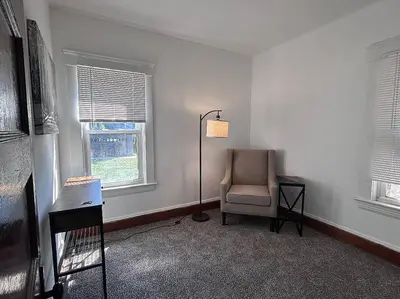 a room with a chair and a lamp and two windows at 2Bed Apt Near University Hospital in East Cleveland