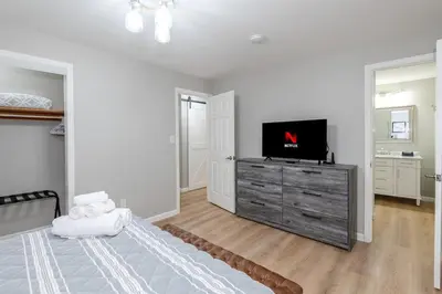 a white bedroom with a television on a dresser at Sweet Magnolia - Newly Remodeled Ranch in Englewood