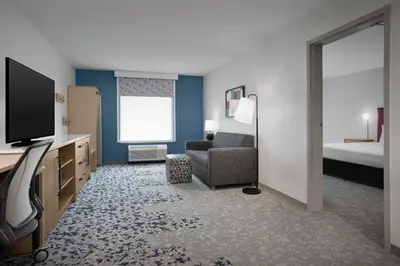 a hotel room with a tv and a chair and a bed at Home2 Suites By Hilton Columbus Easton in Columbus