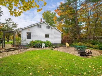 a backyard with a white house and a yard with a yard at Willow Woods Retreat - Farmhouse - Patio & Nature in Kirtland