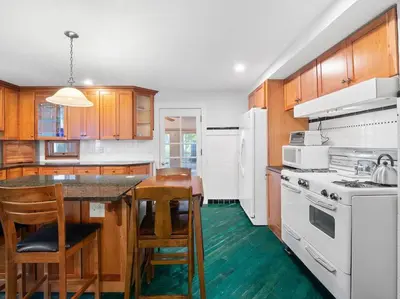 a kitchen with wooden cabinets and a table with chairs at Willow Woods Retreat - Farmhouse - Patio & Nature in Kirtland