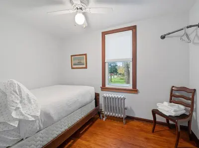 a bedroom with a bed and a chair and a window at Willow Woods Retreat - Farmhouse - Patio & Nature in Kirtland