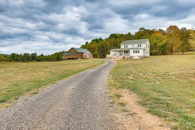a dirt road leading to a house and a field at Wooded Escape with Pond and Grill in Pleasant City! in Senecaville