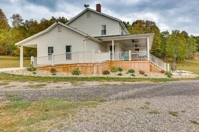 a white house with a porch and a driveway at Wooded Escape with Pond and Grill in Pleasant City! in Senecaville