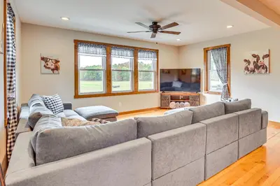 a living room with a large gray couch at Wooded Escape with Pond and Grill in Pleasant City! in Senecaville