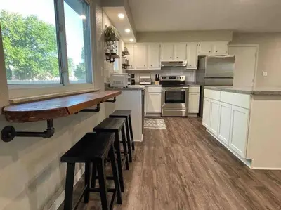 a kitchen with white cabinets and bar stools in it at Spacious 3-bedroom home in Archbold in Archbold