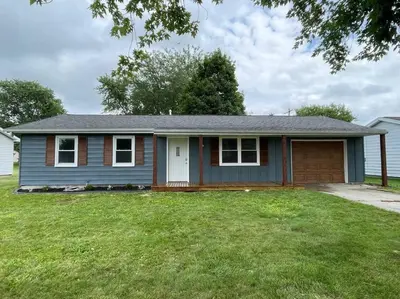 a small blue house with a green yard at Spacious 3-bedroom home in Archbold in Archbold
