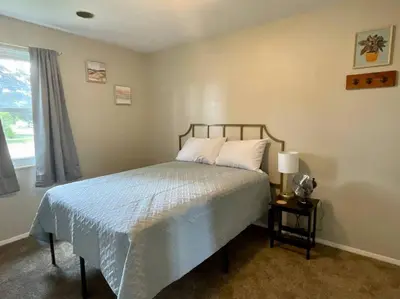 a bedroom with a bed with a blue blanket and a window at Spacious 3-bedroom home in Archbold in Archbold