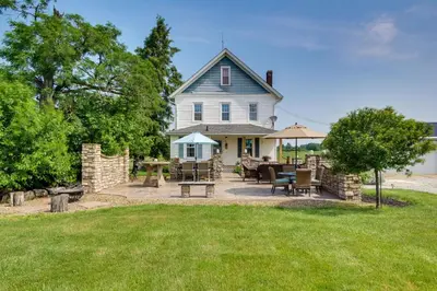 a large white house with a patio with tables and chairs at Countryside Home in Wooster with Patio and Fire Pit in Wooster
