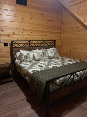 a bedroom with a bed in a log cabin at The Saige - Hot Tub, Fire Pit, and huge entertainment area in Logan