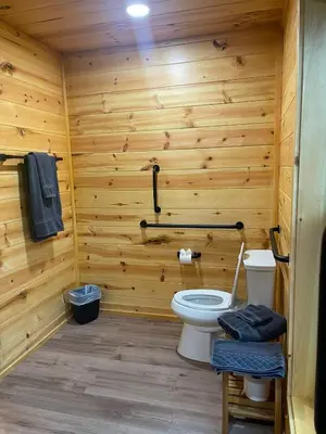 a bathroom with a toilet and a wooden wall at The Saige - Hot Tub, Fire Pit, and huge entertainment area in Logan
