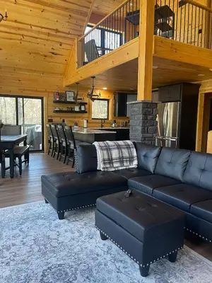 a living room with a black couch and a table at The Saige - Hot Tub, Fire Pit, and huge entertainment area in Logan
