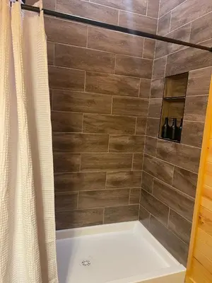 a bathroom with a shower with a white tub at The Saige - Hot Tub, Fire Pit, and huge entertainment area in Logan