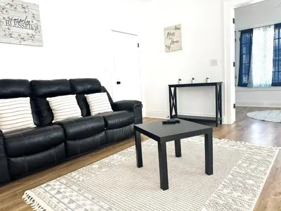 a living room with a black leather couch and a table at Downtown Retreat - Cozy First Floor in Columbus