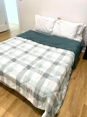 a bed with a plaid comforter and a pillow on it at Downtown Retreat - Cozy First Floor in Columbus