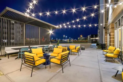 a patio with yellow chairs and tables and lights at Home2 Suites By Hilton Cincinnati Midtown Oakley in Cincinnati