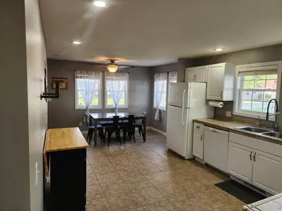 a kitchen and dining room with a table and refrigerator at A spacious getaway on Orchard Island in Russells Point
